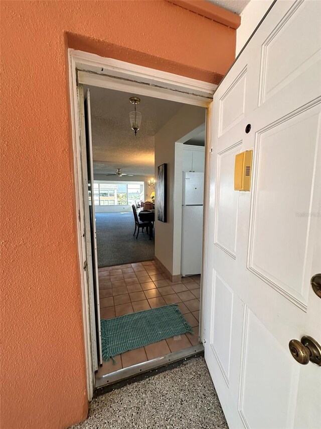 corridor with tile patterned flooring and a textured ceiling