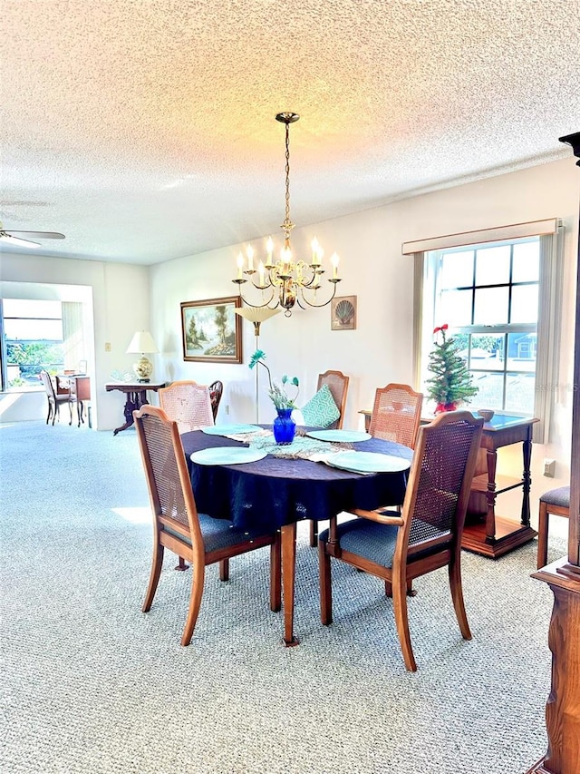 carpeted dining room featuring ceiling fan with notable chandelier and a textured ceiling