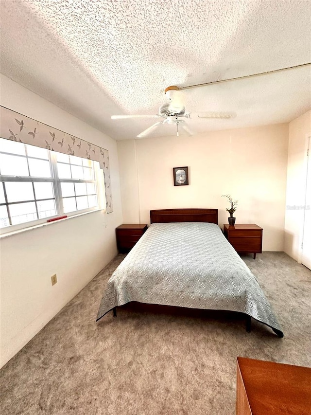 carpeted bedroom with ceiling fan and a textured ceiling