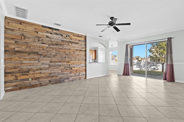 tiled spare room with ceiling fan, wood walls, and ornamental molding