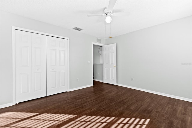 unfurnished bedroom with a textured ceiling, a closet, dark hardwood / wood-style floors, and ceiling fan