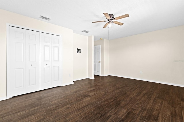 unfurnished bedroom with a closet, dark hardwood / wood-style floors, and ceiling fan