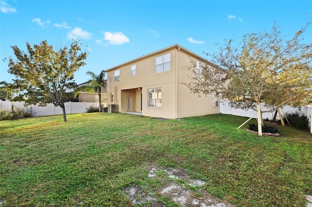 rear view of house with central AC unit and a lawn