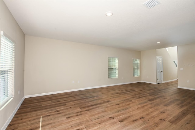 empty room featuring plenty of natural light and dark wood-type flooring