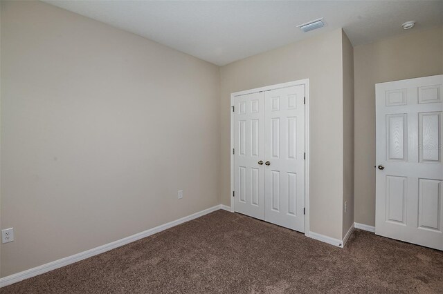 unfurnished bedroom featuring dark colored carpet and a closet