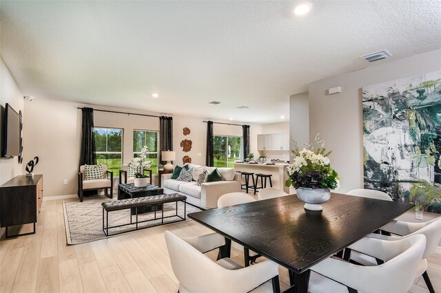 dining space featuring a textured ceiling and light wood-type flooring