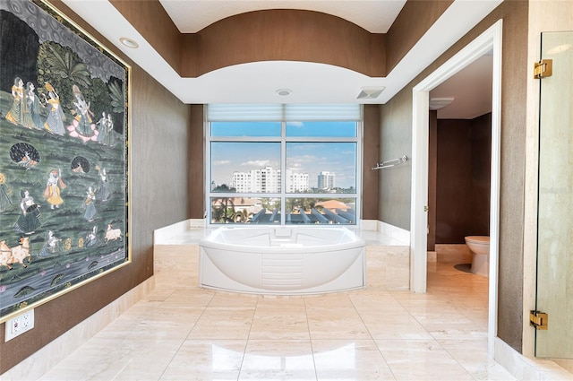 bathroom featuring toilet and a tub to relax in