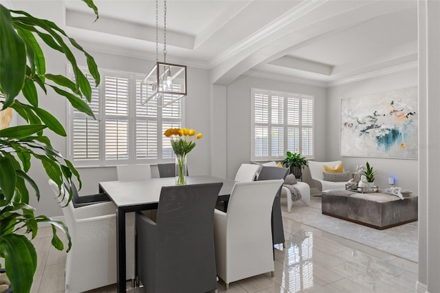 dining area featuring a notable chandelier, a raised ceiling, and crown molding