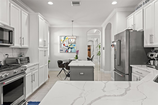 kitchen featuring a kitchen island, high quality appliances, light stone countertops, and white cabinetry