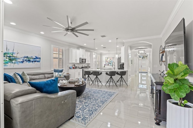 living room featuring ceiling fan, sink, and crown molding