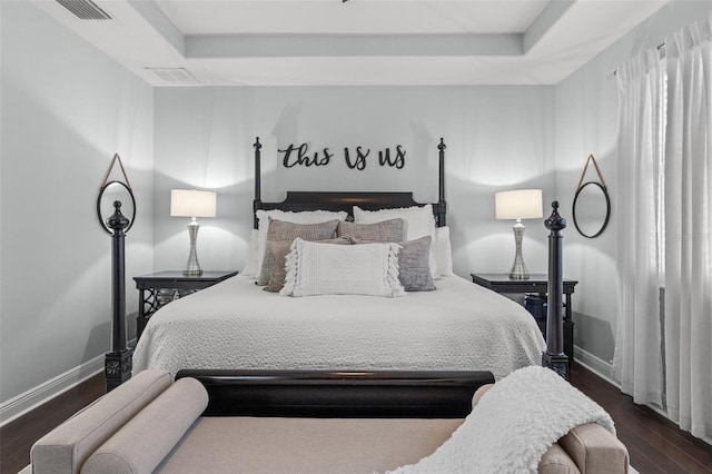 bedroom with a tray ceiling and dark hardwood / wood-style flooring