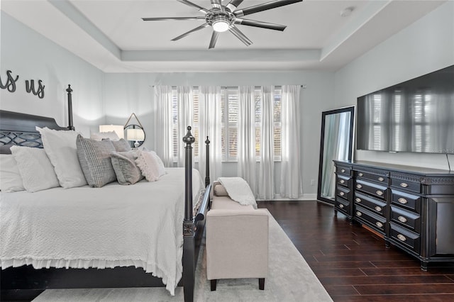 bedroom featuring ceiling fan, a raised ceiling, and dark wood-type flooring