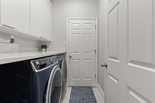 washroom with cabinets and washing machine and clothes dryer