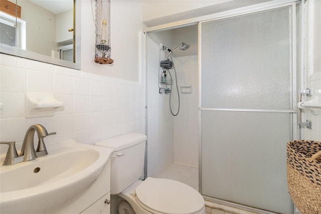 bathroom with vanity, toilet, tile walls, and a shower with shower door