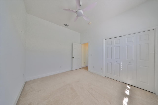 unfurnished bedroom with a closet, light colored carpet, and ceiling fan