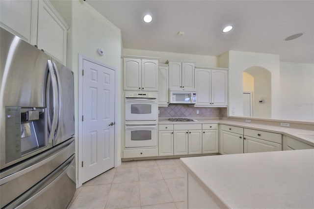 kitchen featuring decorative backsplash, light tile patterned flooring, white cabinetry, and appliances with stainless steel finishes