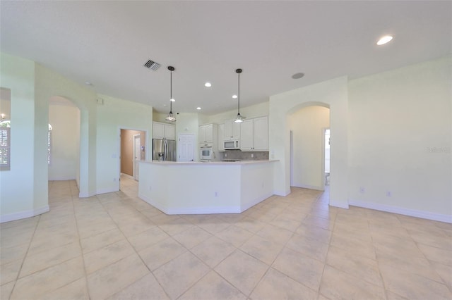 kitchen with light tile patterned floors, white cabinets, decorative light fixtures, and white appliances