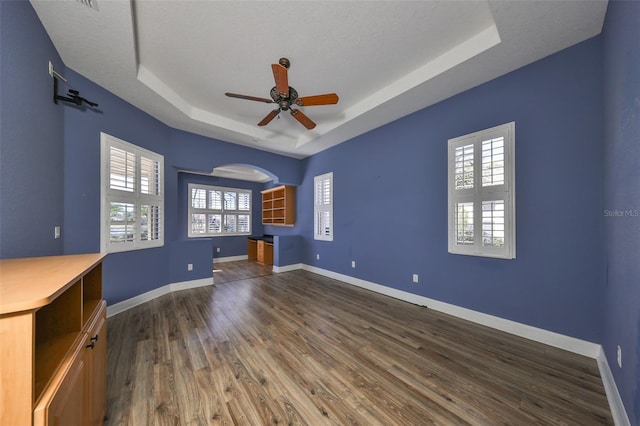 interior space with a raised ceiling, a textured ceiling, and dark hardwood / wood-style floors