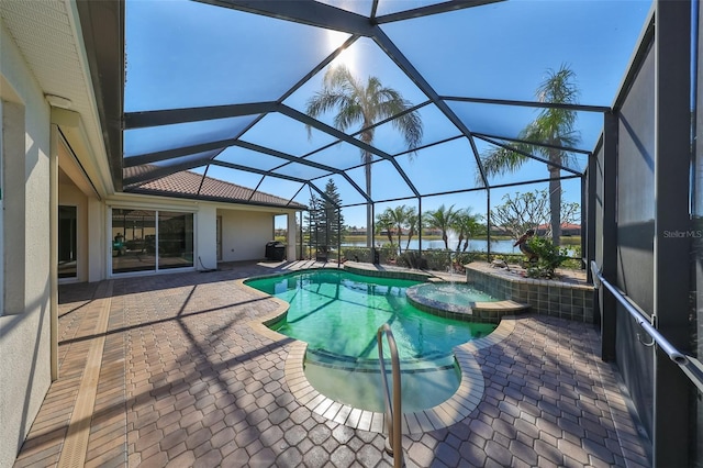 view of pool with an in ground hot tub, a patio, a water view, and glass enclosure