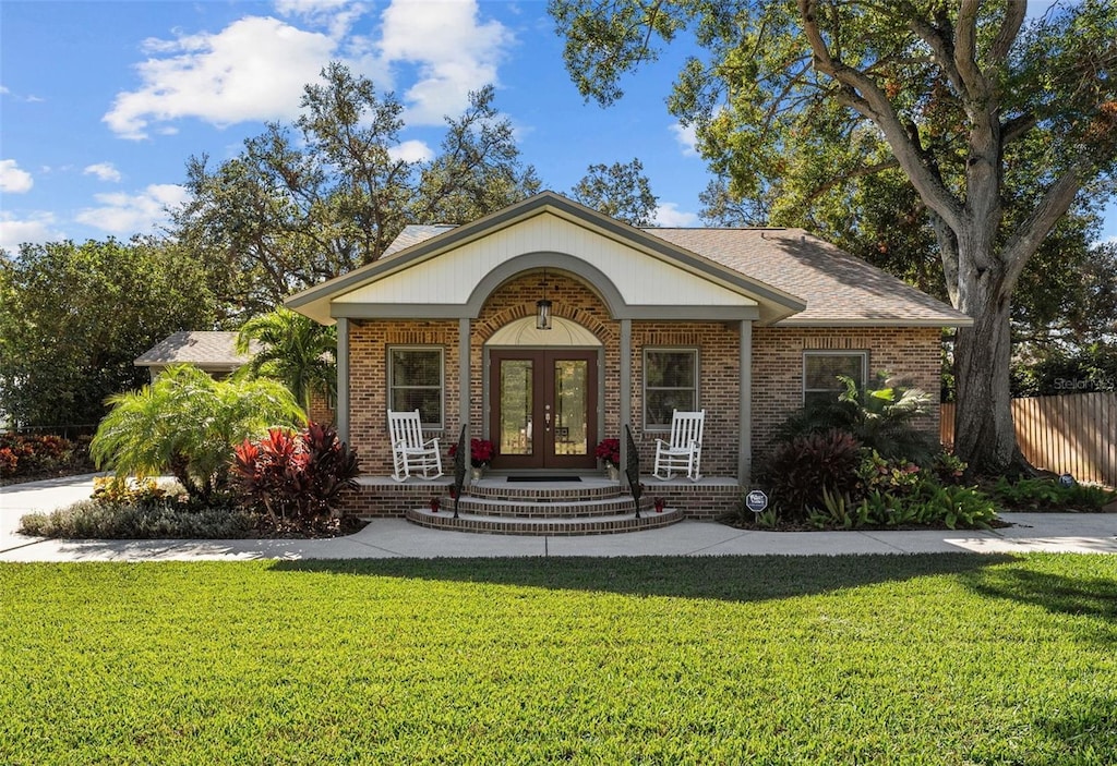 view of front of home with a porch, french doors, and a front yard