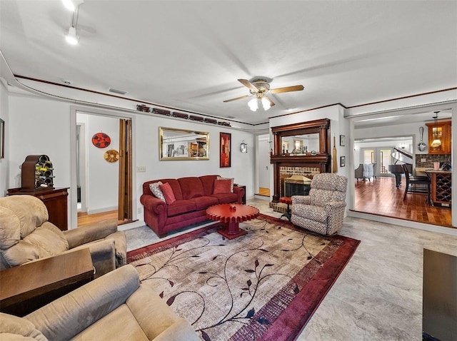 living room featuring ceiling fan, a fireplace, and light wood-type flooring