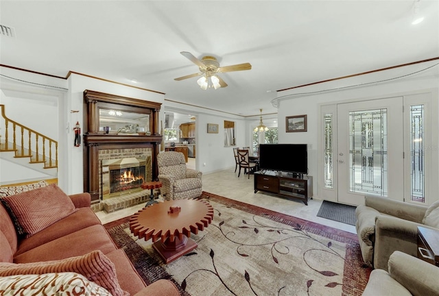 living room with a fireplace, a healthy amount of sunlight, crown molding, and ceiling fan