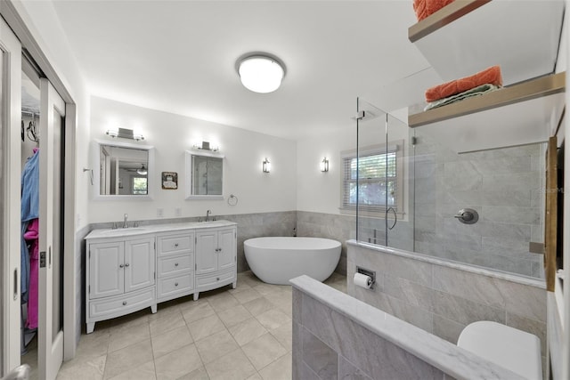 bathroom featuring tile patterned flooring, vanity, tile walls, and plus walk in shower