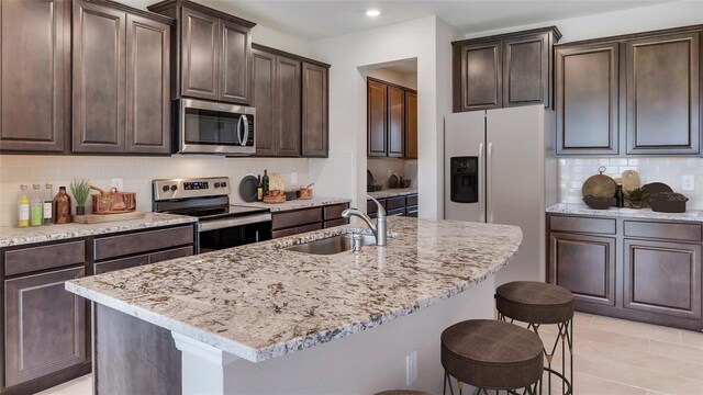 16033 7th Ave E, Bradenton, FL 34212 - kitchen with appliances with stainless steel finishes, a sink, a kitchen breakfast bar, decorative backsplash, and dark brown cabinets