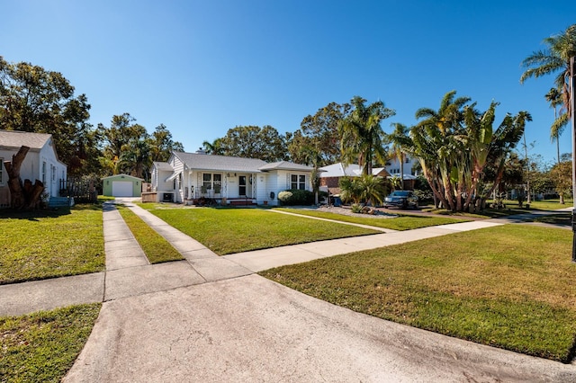 single story home featuring central AC unit, a garage, an outbuilding, and a front yard