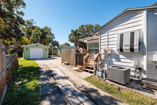 exterior space with cooling unit, a garage, an outbuilding, and a wooden deck