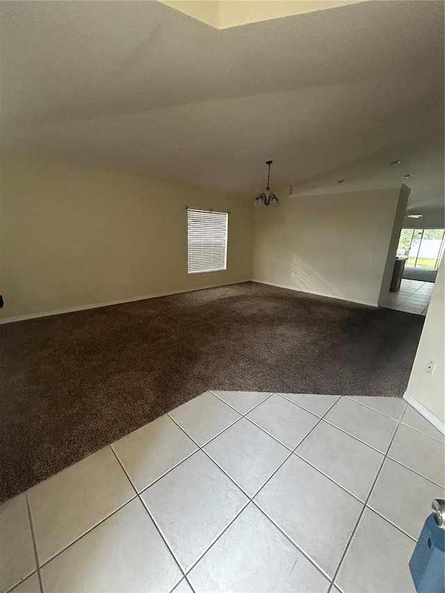 tiled empty room with an inviting chandelier and lofted ceiling