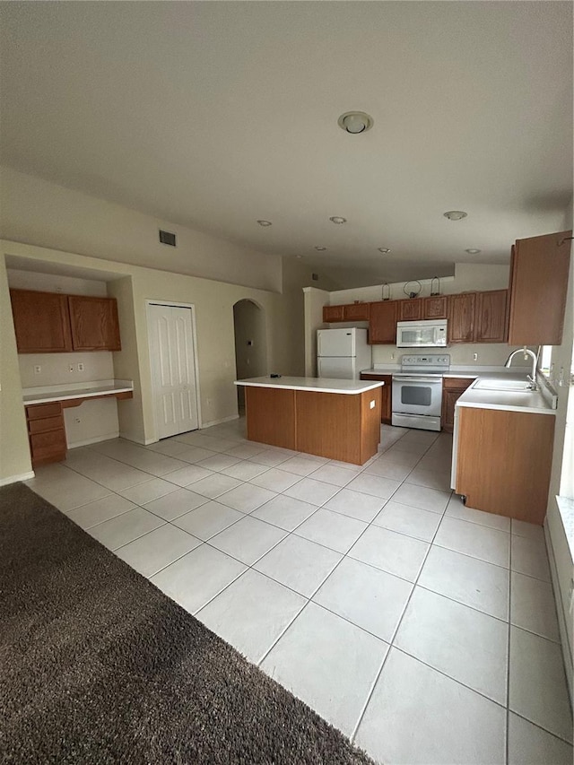 kitchen featuring light tile patterned flooring, white appliances, a center island, and sink