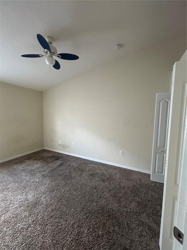 spare room featuring dark carpet and ceiling fan