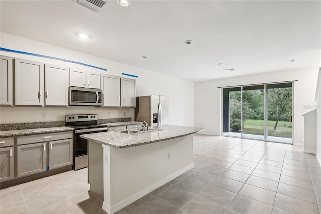 kitchen featuring sink, light tile patterned floors, stainless steel appliances, and an island with sink