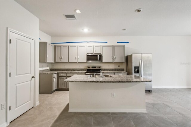 kitchen featuring gray cabinetry, stainless steel appliances, and a kitchen island with sink