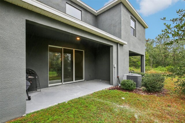 rear view of house featuring a lawn, a patio, and central AC