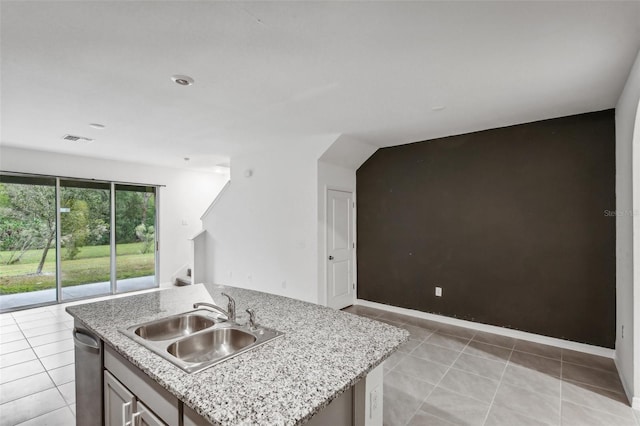 kitchen featuring a center island with sink, light stone countertops, light tile patterned floors, and sink