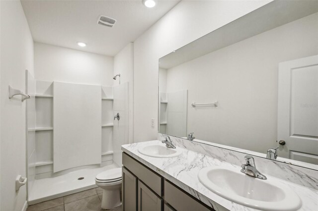 bathroom featuring a shower, tile patterned flooring, vanity, and toilet