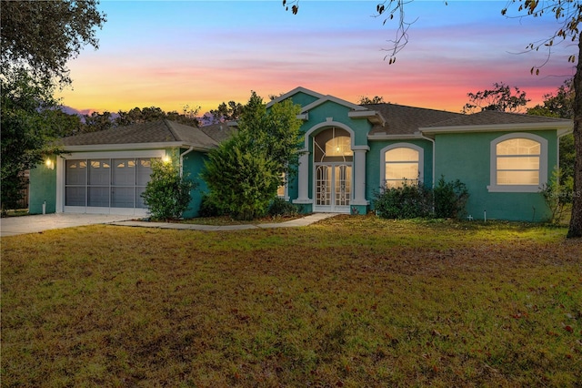 ranch-style house with a garage, a yard, and french doors