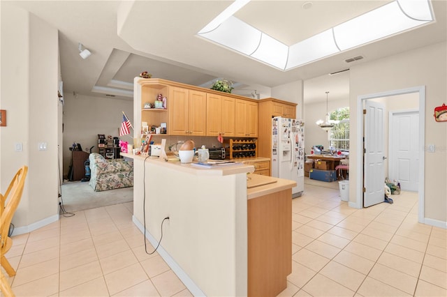 kitchen featuring kitchen peninsula, light brown cabinetry, backsplash, white fridge with ice dispenser, and light tile patterned flooring