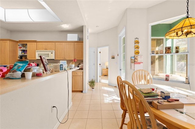 kitchen with light brown cabinets, light tile patterned floors, and decorative light fixtures