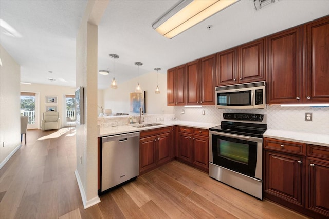 kitchen with light hardwood / wood-style floors, sink, stainless steel appliances, and hanging light fixtures