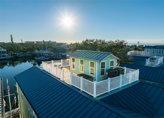 back of property featuring a water view and central AC unit