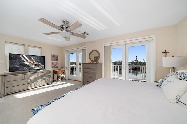 carpeted bedroom with access to exterior, ceiling fan, and a water view