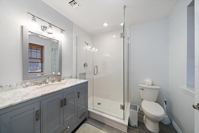 bathroom with a shower with door, vanity, and toilet