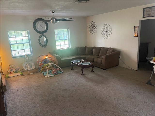 living room with plenty of natural light, ceiling fan, carpet floors, and a textured ceiling