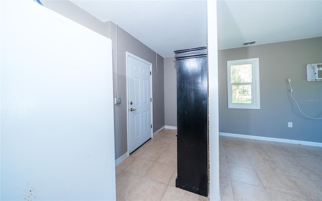 hall featuring a wall unit AC and light tile patterned floors