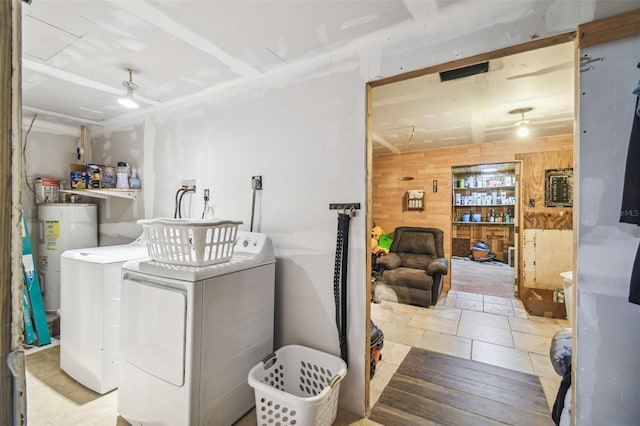 washroom with electric water heater, wood walls, and separate washer and dryer