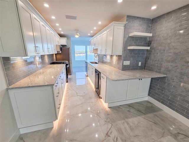 kitchen with tasteful backsplash, white cabinetry, sink, a water view, and light stone countertops