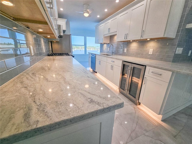 kitchen with wine cooler, sink, light stone counters, and white cabinets